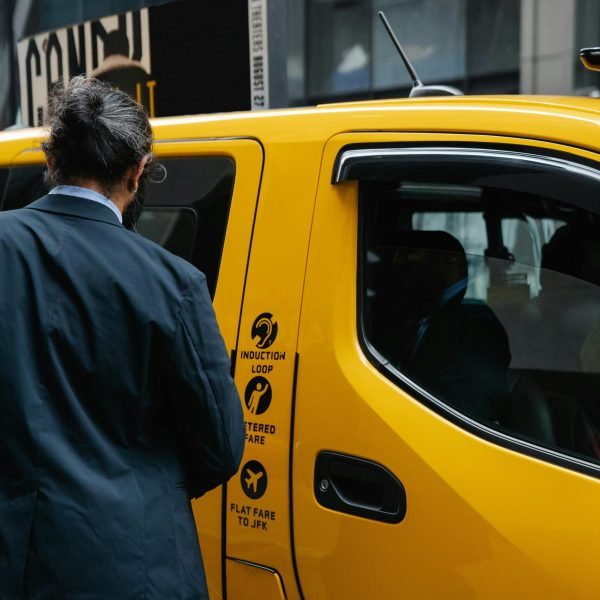 Businessman in suit entering a yellow NYC taxi, a classic urban transportation scene.